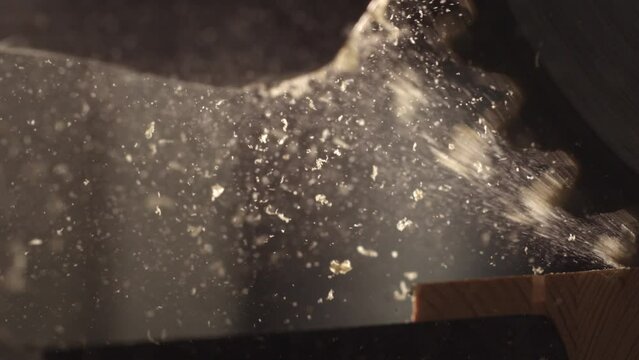 4K video of the last Moment an electric saw cutting wood. Sawdust and wood chips flying in slow motion