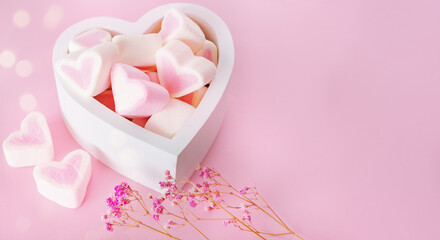 Pink marshmallows in the shape of hearts lie in a wooden box on a pink background with copy space and bokeh. Valentine's Day, Mother's Day, Father's Day, Wedding. Sweet confectionery product.