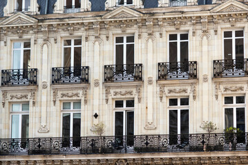 Facade with windows in an old tenement house in France, French architecture.