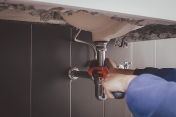 plumber at work in a bathroom, plumbing repair service , fix water plumbing leaks, replace the kitchen sink drain