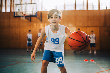 A junior basketball player is dribbling a ball during his training.