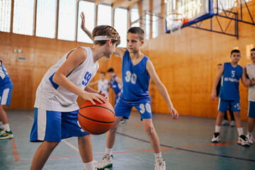 Naklejka premium A junior team practicing basketball on training at indoor court.