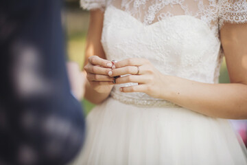 bride holding a wedding ring to the groom. bride holds hands at wrist with wedding ring, close-up view of hands, love and family concept. 