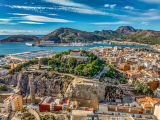 Aerial view of Cartagena port city in Spain surrounded by bastions and fortifications, medieval castle hill, roman amphitheater, bull ring,  - obrazy, fototapety, plakaty