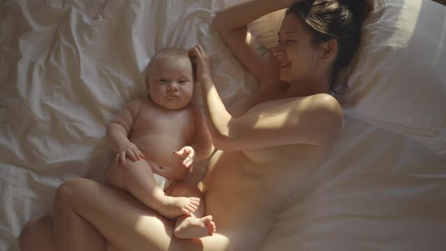 Very intimate moment of Beautiful young woman in warm cozy bedroom breastfeeding her little newborn baby, enjoy moment of tenderness, feeling unconditional love. Lactation of child, natural nutrition