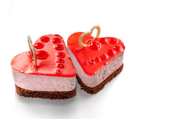 Red glazed cheese cake in the shape of a heart with fruit jelly decoration. Exquisite Fresh delicious mousse dessert on white isolated background with shadow.