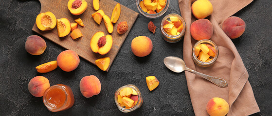 Cut fresh peaches and sweet jam in jar on grunge dark background