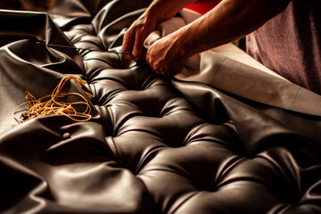 upholsterer's hands creating a diamond-tufted headboard - obrazy, fototapety, plakaty