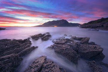 Obraz premium Sonabia beach at sunrise with the Sonabia beach at sunrise with the water between the rocks in the foreground
