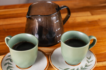 two cups of coffee and strainer used in the background