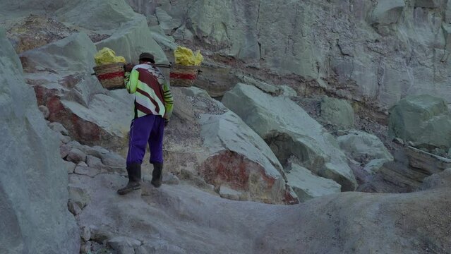 Miner carrying baskets of sulphur mined from Kawah Ijen volcano, Java, Indonesia