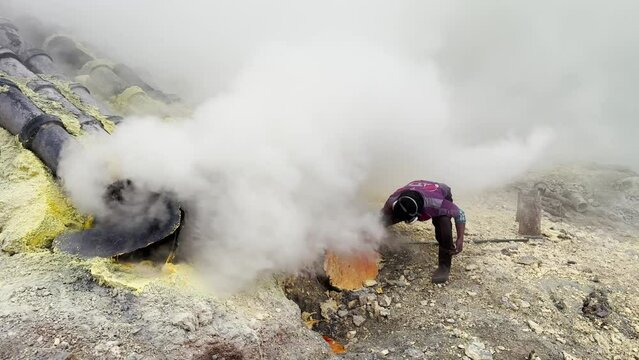 Miner extracting sulfur from Kawah Ijen volcano crater in Java, Indonesia