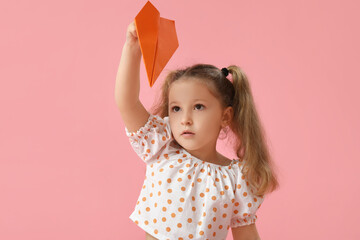 Cute little girl with paper plane on pink background