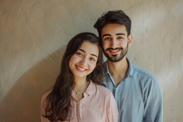 Portrait of a happy young couple smiling together against a neutral background.