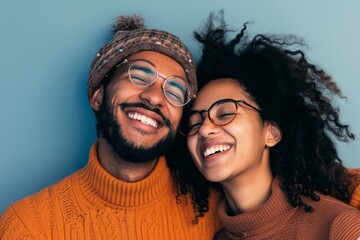 Happy couple in winter attire laughing against a blue background.