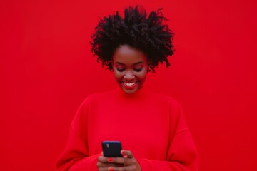 Happy African Woman In Red Sweatshirt Checks Phone Against Red Backdrop