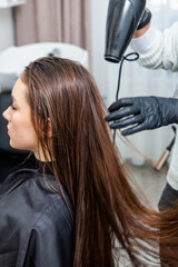 Fototapeta premium Photo of a European girl with long and beautiful brunette hair at the beauty salon. Shiny and healthy hair