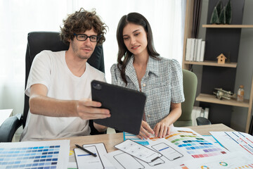 Caucasian businessman and Asia businesswoman working with tablet computer and color chart at office	