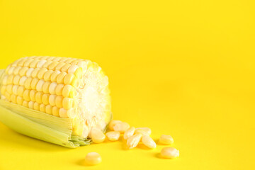 Cut fresh corn cob and seeds on yellow background