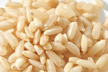 A background of dry brown rice grains showcases the integral, uncooked basmati texture. The macro view highlights the raw nature of this organic, whole food.