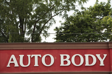 auto body caption writing text white on red background mechanic shop with trees and sky in...