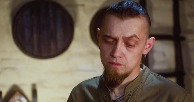 Uncertain man in medieval restaurant closeup. Guest with dark goatee thinks about difficult question in old hotel. Dark ages fantasy and role play game