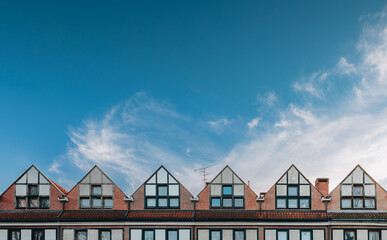 A view of a row of pointed roofs against a blue sky. 