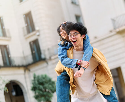 woman couple man happy hugging love young together piggyback travel tourist romantic hugging outside city vacation student smile fun relationship joy bonding