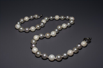 Pearl white round beads on a gray background. Women's elegant jewelry.