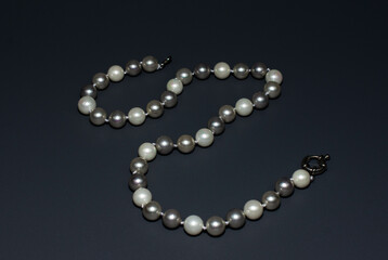 Pearl white round beads on a gray background. Women's elegant jewelry.