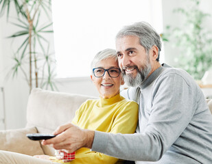 television watching senior couple tv home woman man remote movie mature old aged active vitality elderly pensioner retired entertainment sofa retirement sitting fun beautiful