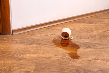 Wooden laminate floor with overturned cup of tea