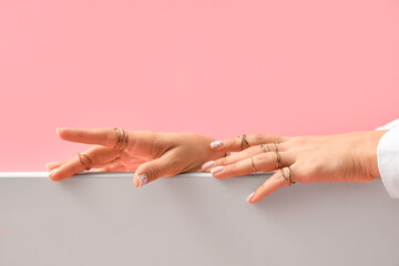 Woman with golden rings on color background, closeup