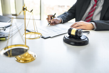 Male lawyer or judge working with contract papers, Law books and wooden gavel on table in...