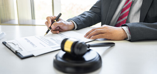 Male lawyer or judge working with contract papers, Law books and wooden gavel on table in...