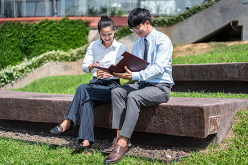 Young business woman holding coffee cup and reading document paper with businessman