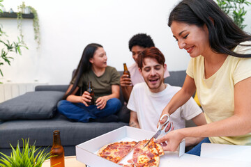 Close-knit friends share a laugh while eating pizza and drinking beers, celebrating together in a snug and festive atmosphere.