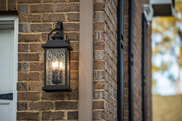 An outdoor black classic and traditional gas lantern on the exterior of a brown brick house home © Ursula Page