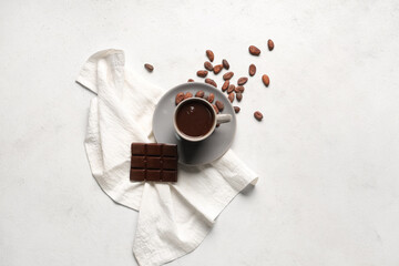Plate with cup of tasty hot chocolate, cocoa beans and napkin on white grunge background