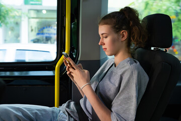 Girl with a phone rides in a minivan taxi.