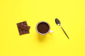 Cup of tasty hot chocolate with spoon on yellow background