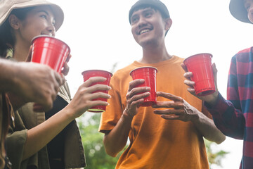 Cheers! Group of asian people friend party camping in nature making toasting with soft drink and...