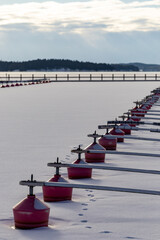 Dalaro, Sweden A small boat dock with red buoys with no boats in the ice on the Baltic Sea.