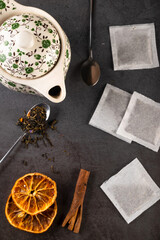 Tea composition teapot and teacup with tea bags on dark background.