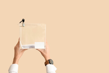 Hands holding ballot box on beige background. Election concept