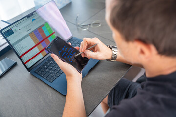 Close up view of man hand holding smart phone and stylus pen at his creative workspace. 