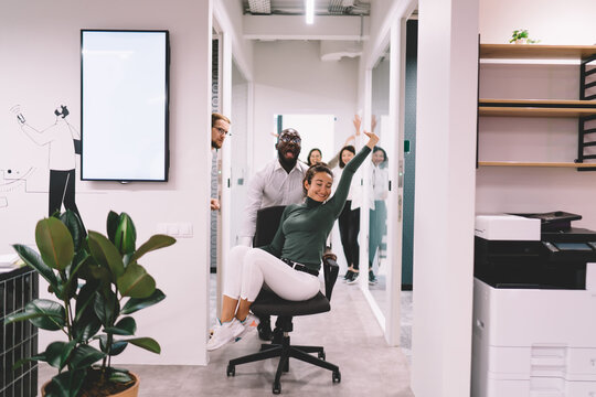 Funny diverse coworkers rolling woman on office chair - Powered by Adobe