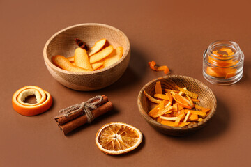 Composition with bowls of orange peel and cinnamon on color background