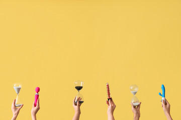 Female hands holding hourglasses and vibrators on yellow background