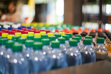 Lot of blue plastic half-liter small volume mineral water bottles, green yellow red cap in store,...